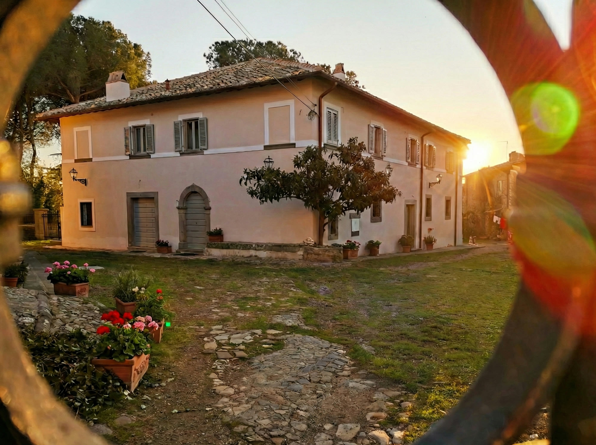 The facade of Corte Signoretti at sunset, seen through the wrought-iron gate